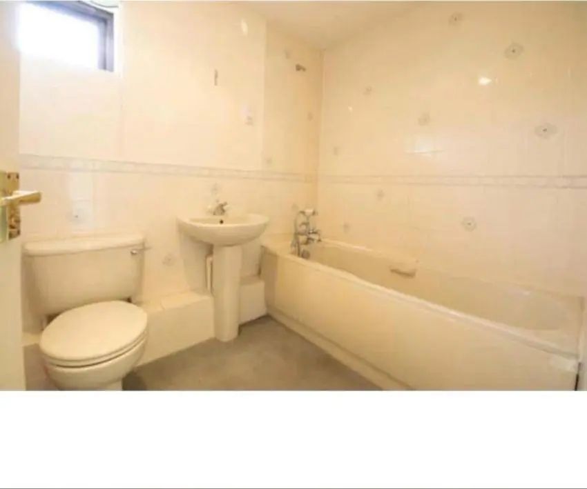Bathroom before renovation — dated cream suite and tiles