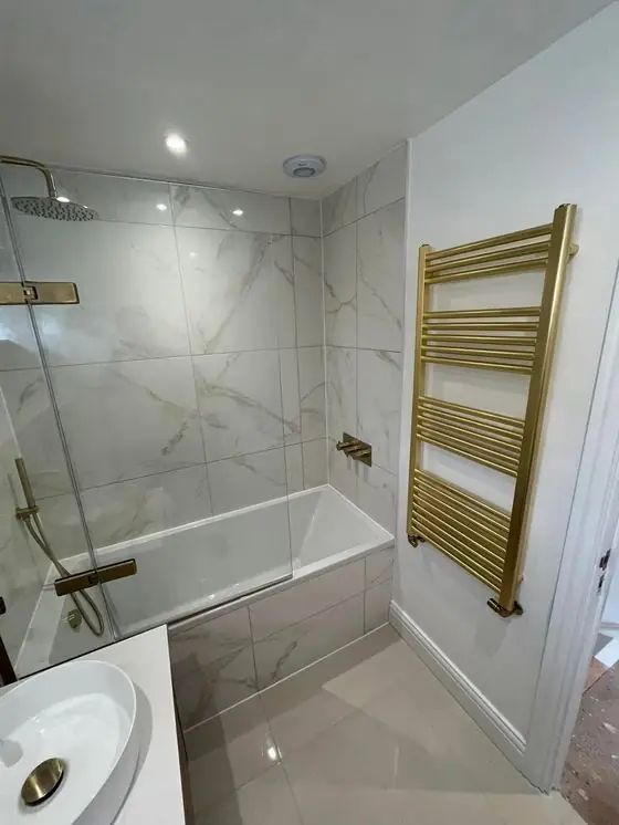 Finished bathroom with bath, brass shower and heated towel rail
