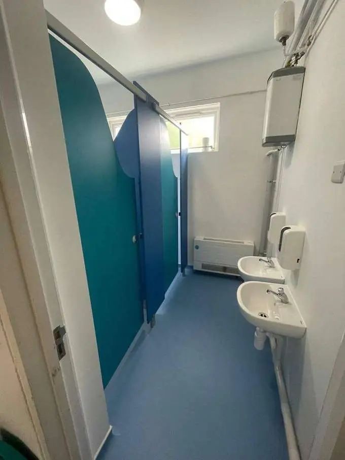 Finished primary school washroom — blue vinyl, teal cubicles, modern sinks