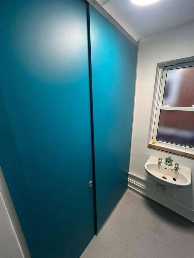 Finished school washroom — teal cubicles and new flooring