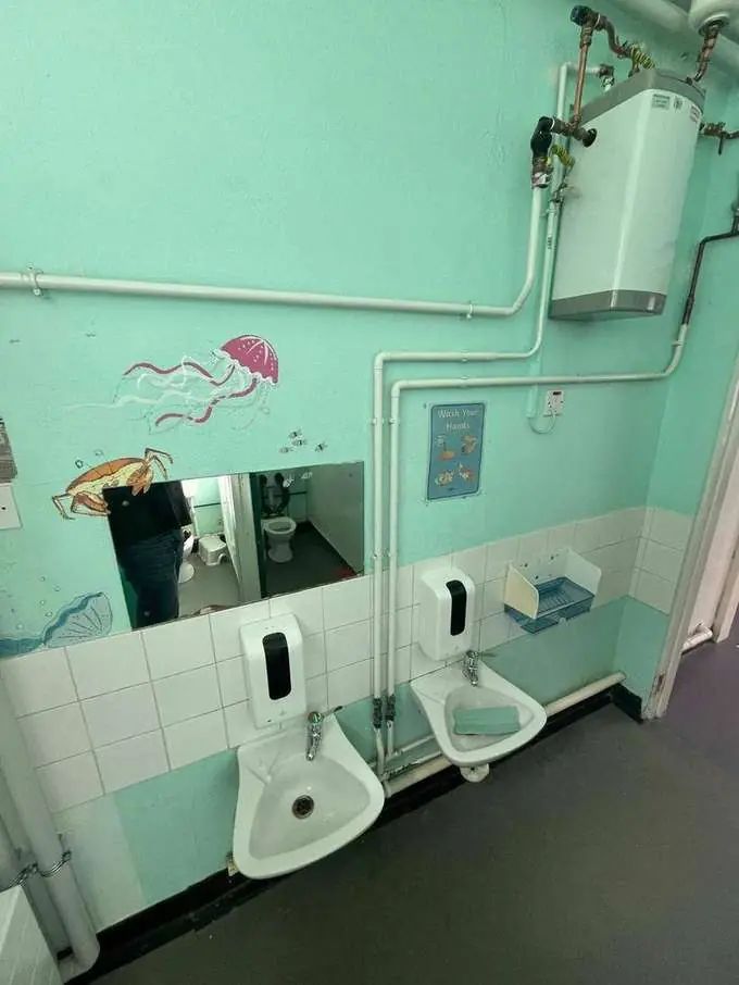 Primary school washroom before — dated mint green, old sanitary ware