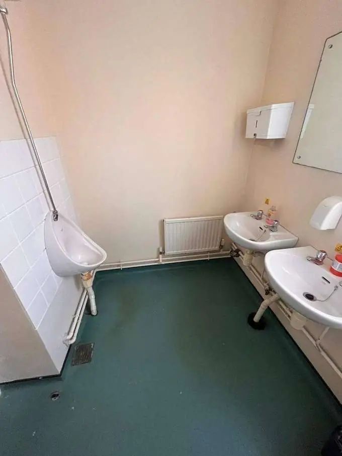 School washroom before — old urinal, exposed pipes, tired finishes
