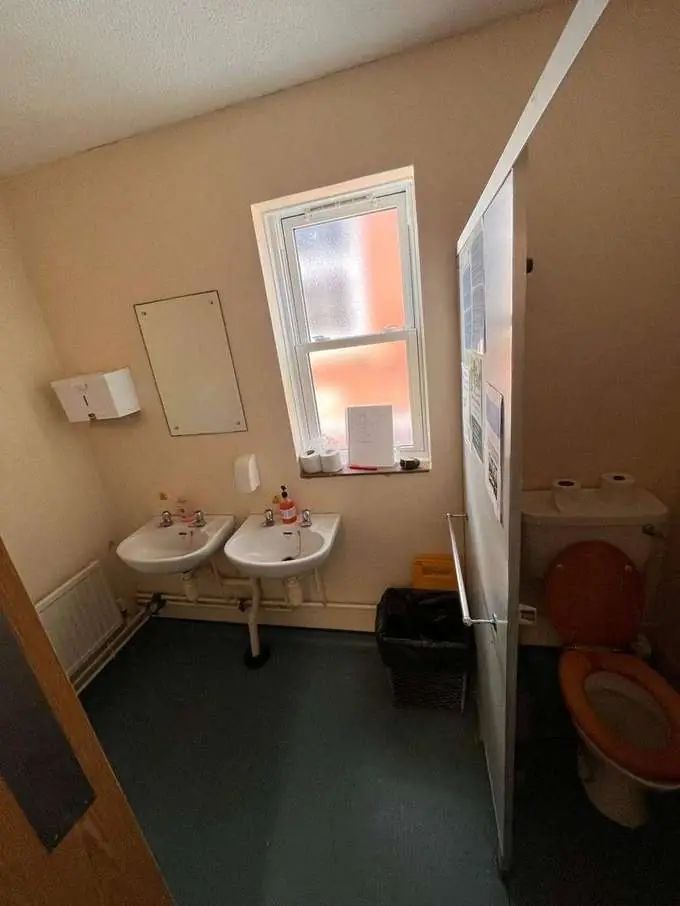 School washroom before — worn sinks and dated decoration