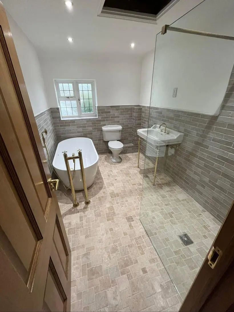 Traditional bathroom with freestanding bath, brass fittings and grey brick tiling