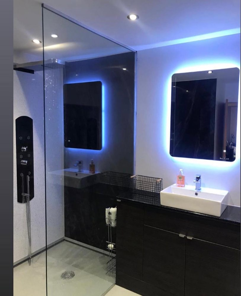 Level-access wet room with a walk-in glass screen, black shower tower and twin counter-top basins